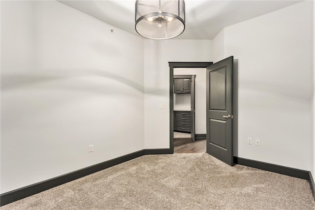 27 Library St NE Unit 301, Grand Rapids, MI 49503 - spare room featuring carpet, a chandelier, and baseboards