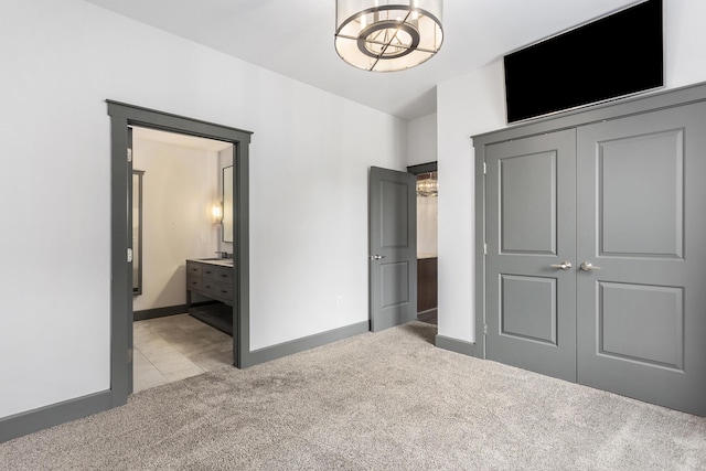 27 Library St NE Unit 301, Grand Rapids, MI 49503 - unfurnished bedroom with light colored carpet, a closet, a chandelier, ensuite bath, and baseboards