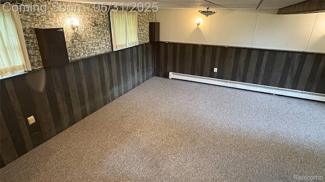 8865 E Bennington Rd, Durand, MI 48429 - spare room featuring a baseboard heating unit, wainscoting, carpet floors, and wooden walls