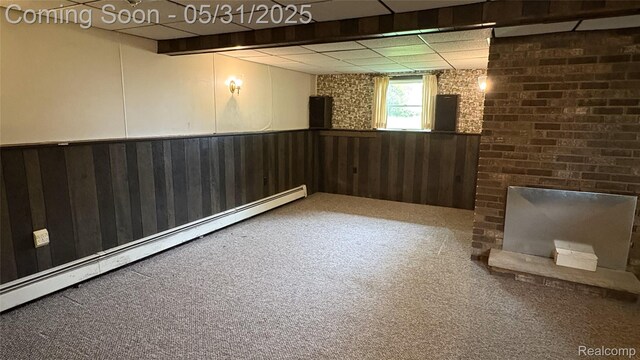 8865 E Bennington Rd, Durand, MI 48429 - below grade area featuring carpet floors, a baseboard radiator, a wainscoted wall, a drop ceiling, and wooden walls