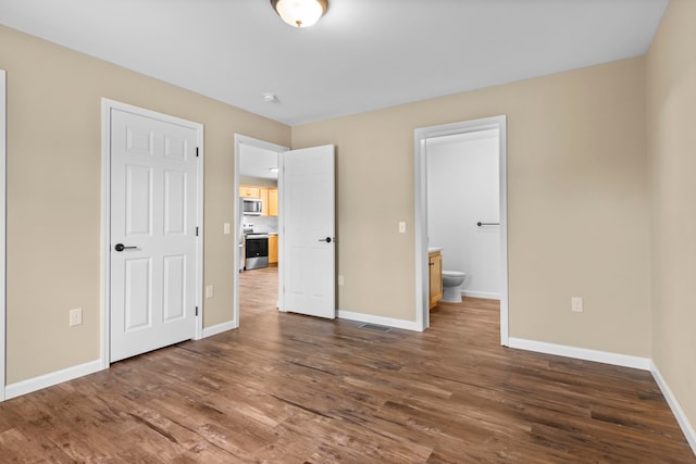 8524 S Elizabeth Dr, Maple City, MI 49664 - unfurnished bedroom with dark wood-style flooring, baseboards, and ensuite bathroom