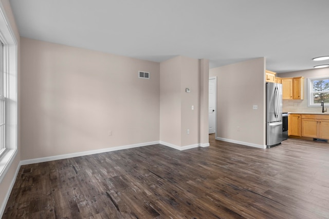 8524 S Elizabeth Dr, Maple City, MI 49664 - unfurnished living room featuring dark wood-style flooring, baseboards, and a sink