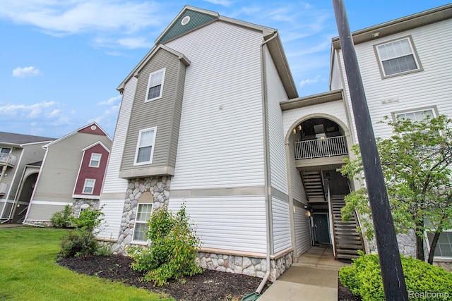 15200 Silver Pkwy Unit 101, Fenton, MI 48430 - view of home's exterior with stairs, a balcony, stone siding, and a yard