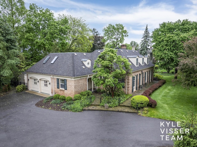600 Plymouth Ave SE, East Grand Rapids, MI 49506 - view of front of property with asphalt driveway, a front lawn, brick siding, a chimney, and roof with shingles