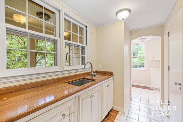 600 Plymouth Ave SE, East Grand Rapids, MI 49506 - kitchen featuring a sink, arched walkways, crown molding, baseboards, and light tile patterned floors