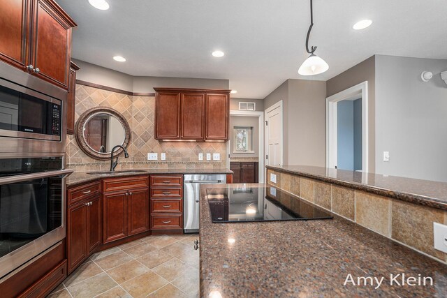 1657 N Bay Dr, Hudsonville, MI 49426 - kitchen featuring appliances with stainless steel finishes, a sink, tasteful backsplash, hanging light fixtures, and dark stone counters