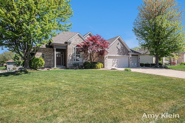 1657 N Bay Dr, Hudsonville, MI 49426 - view of front of house with driveway, a front lawn, an attached garage, and stone siding