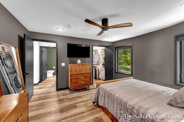18619 130th Ave, Fruitport, MI 49415 - bedroom featuring stacked washer / dryer, light wood-type flooring, a walk in closet, a closet, and a ceiling fan