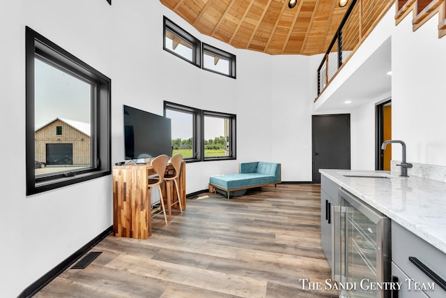 18619 130th Ave, Fruitport, MI 49415 - living area featuring beverage cooler, wooden ceiling, light wood finished floors, baseboards, and a high ceiling