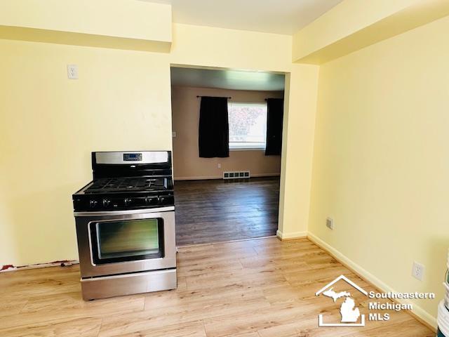 8499 Armstrong Rd, Newport, MI 48166 - kitchen featuring stainless steel gas stove, wood finished floors, and baseboards