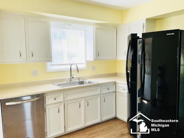 8499 Armstrong Rd, Newport, MI 48166 - kitchen featuring freestanding refrigerator, dishwasher, a sink, and white cabinets