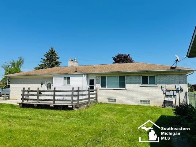 8499 Armstrong Rd, Newport, MI 48166 - back of property featuring a yard, a deck, brick siding, and a chimney