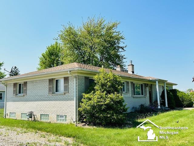 8499 Armstrong Rd, Newport, MI 48166 - view of side of property with a chimney, brick siding, and a yard