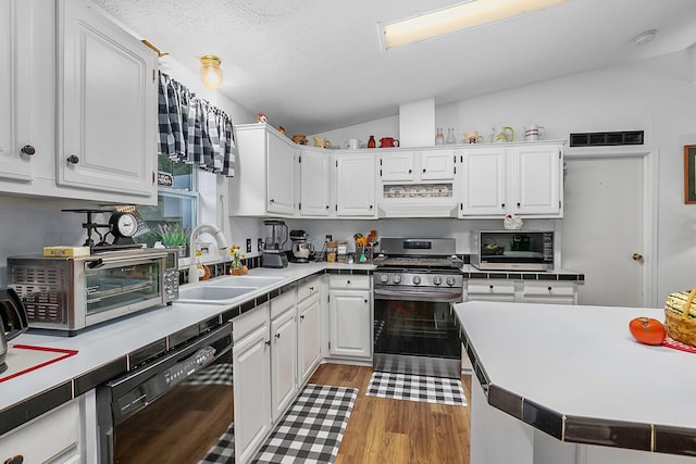 11478 E 7 Mile Rd, Tustin, MI 49688 - kitchen with stainless steel appliances, a sink, lofted ceiling, white cabinets, and light wood-style flooring