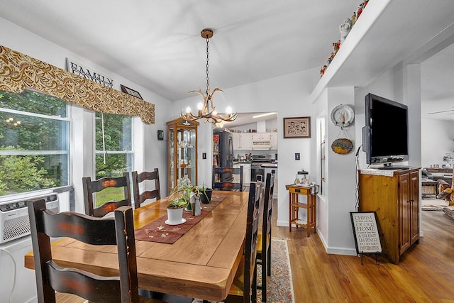 11478 E 7 Mile Rd, Tustin, MI 49688 - dining space featuring a chandelier, wood finished floors, cooling unit, and lofted ceiling