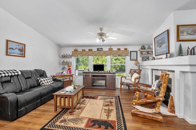 11478 E 7 Mile Rd, Tustin, MI 49688 - living room with a tiled fireplace, wood finished floors, a ceiling fan, and cooling unit