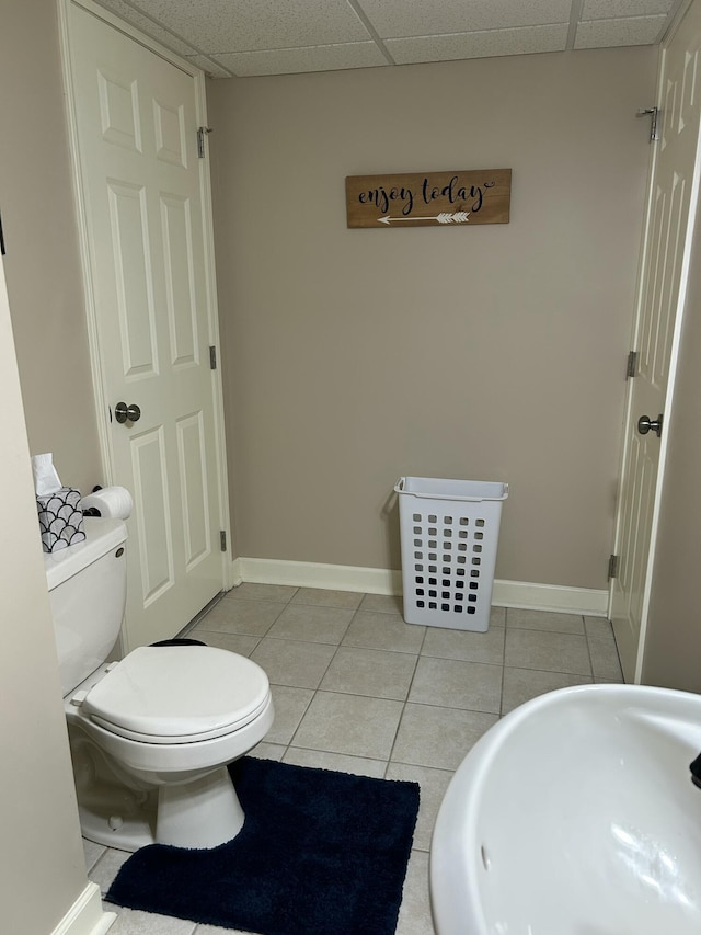 14278 Tyson Trl, Camden, MI 49232 - bathroom featuring toilet, tile patterned flooring, a paneled ceiling, a sink, and baseboards