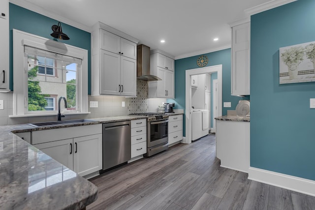1406 W Washington Ave, Jackson, MI 49203 - kitchen with appliances with stainless steel finishes, wall chimney exhaust hood, a sink, crown molding, and tasteful backsplash