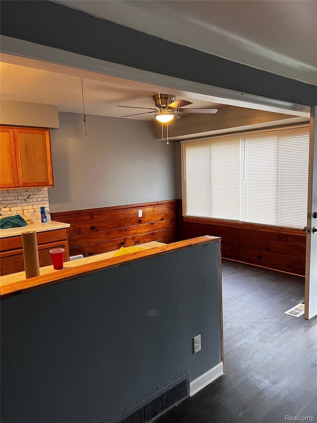 8208 Kentucky St, Detroit, MI 48204 - kitchen featuring wooden walls, brown cabinets, a wainscoted wall, ceiling fan, and dark wood finished floors