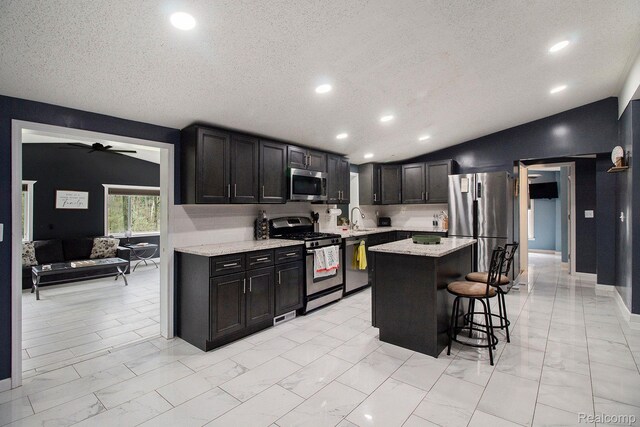 5315 Brown Rd, Millington, MI 48746 - kitchen featuring appliances with stainless steel finishes, light marble finish floors, a textured ceiling, a sink, and a kitchen breakfast bar