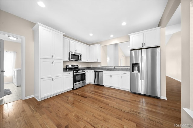3021 Berkshire Rd, Auburn Hills, MI 48326 - kitchen featuring appliances with stainless steel finishes, light wood finished floors, white cabinetry, a sink, and dark countertops