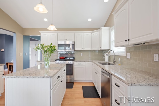 5348 Cristo Dr NE, Rockford, MI 49341 - kitchen featuring stainless steel appliances, a sink, light wood finished floors, a center island, and white cabinetry