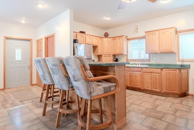 10138 S Lakeside Ridge Rd, Baldwin, MI 49304 - kitchen with light brown cabinets, freestanding refrigerator, a kitchen bar, and ceiling fan