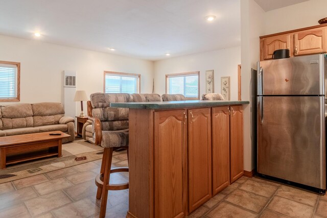 10138 S Lakeside Ridge Rd, Baldwin, MI 49304 - kitchen with freestanding refrigerator, a kitchen bar, open floor plan, a peninsula, and dark countertops