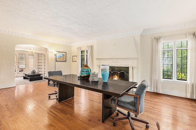 3261 Sherbourne Rd, Detroit, MI 48221 - dining room with a textured ceiling, arched walkways, wood finished floors, baseboards, and a premium fireplace