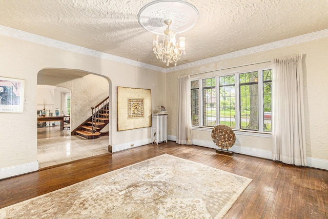 3261 Sherbourne Rd, Detroit, MI 48221 - foyer entrance featuring a textured ceiling, radiator heating unit, arched walkways, wood-type flooring, and a chandelier