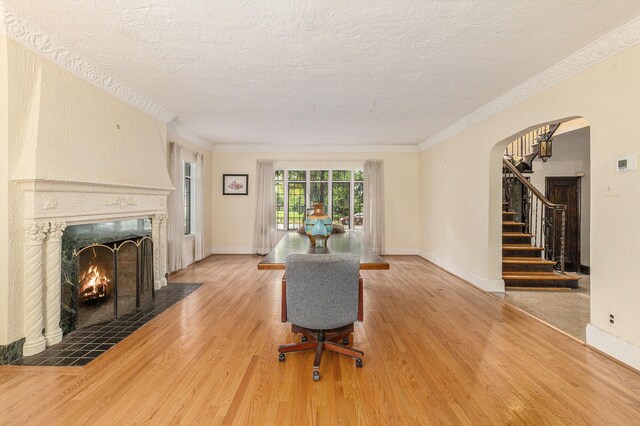 3261 Sherbourne Rd, Detroit, MI 48221 - living room featuring wood finished floors, arched walkways, a textured ceiling, a fireplace with flush hearth, and stairway