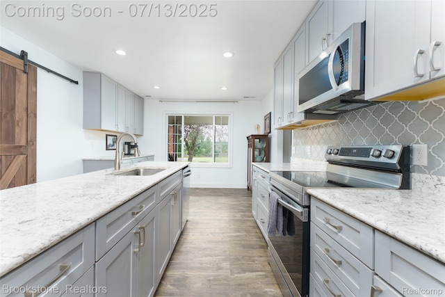 6245 Ray Rd, Swartz Creek, MI 48473 - kitchen with stainless steel appliances, dark wood finished floors, a barn door, recessed lighting, and gray cabinetry
