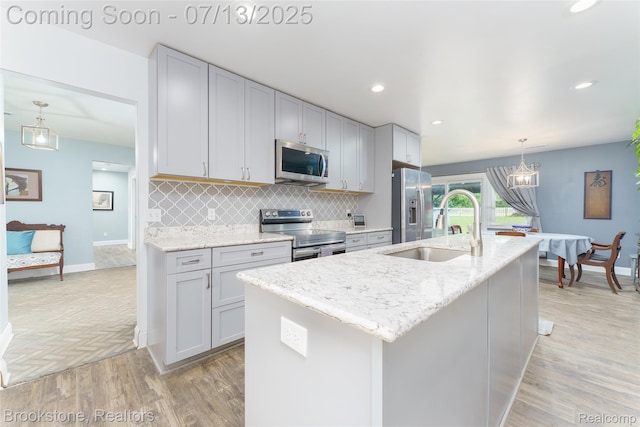6245 Ray Rd, Swartz Creek, MI 48473 - kitchen with stainless steel appliances, light wood finished floors, backsplash, an island with sink, and light stone countertops