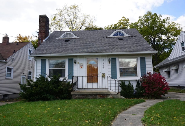 1916 Lyons Ave, Lansing, MI 48910 - view of front of home with a front yard, a shingled roof, and a chimney