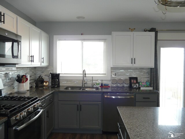 12067 Lewis Ave, Temperance, MI 48182 - kitchen with black gas stove, stainless steel dishwasher, a sink, decorative backsplash, and dark stone counters