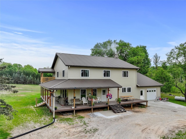 8875 N Lakola Rd, Tustin, MI 49688 - view of front facade featuring an attached garage, dirt driveway, covered porch, metal roof, and a front yard