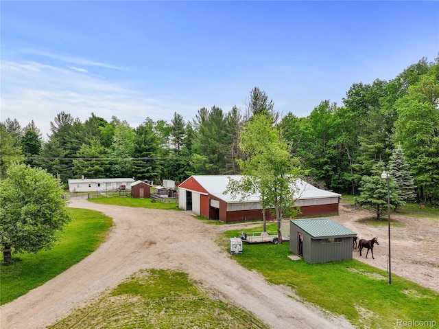 8875 N Lakola Rd, Tustin, MI 49688 - view of front of house with driveway, an outdoor structure, an outbuilding, a detached garage, and metal roof