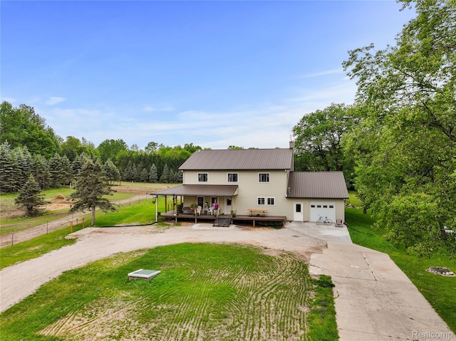 8875 N Lakola Rd, Tustin, MI 49688 - view of front facade with concrete driveway, a garage, metal roof, and covered porch