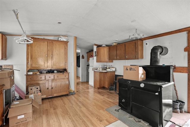 8875 N Lakola Rd, Tustin, MI 49688 - kitchen with brown cabinetry, light wood finished floors, a wood stove, lofted ceiling, and freestanding refrigerator
