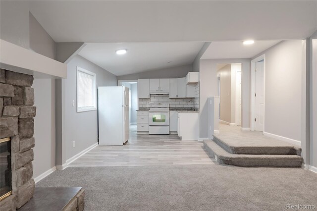 38204 Main St, New Baltimore, MI 48047 - kitchen with white appliances, light colored carpet, under cabinet range hood, white cabinets, and a fireplace