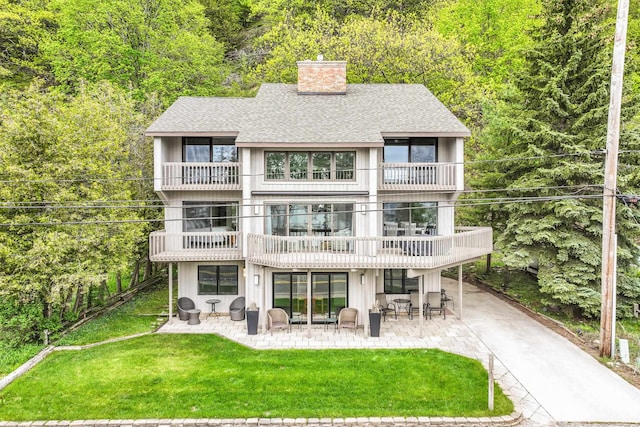 4312 Crystal Dr, Beulah, MI 49617 - back of house featuring a balcony, a patio, a shingled roof, and a chimney