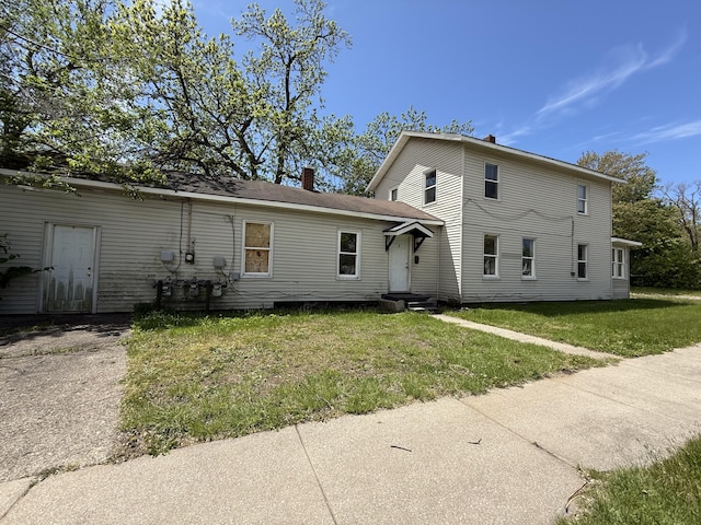 391 Monroe Ave, Muskegon, MI 49441 - back of house with entry steps, a lawn, and a chimney