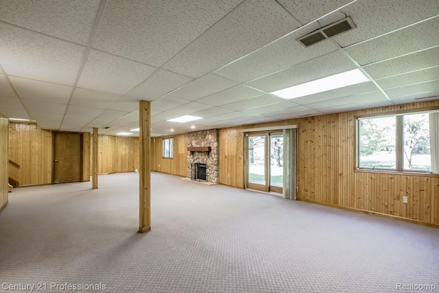 943 N Hacker Rd, Howell, MI 48843 - basement featuring a paneled ceiling, wood walls, a stone fireplace, and carpet floors