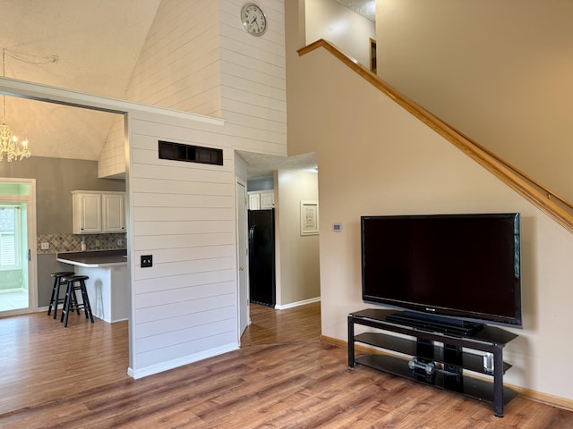 6981 Jennifer Ln, Portland, MI 48875 - living room featuring wood finished floors, a chandelier, high vaulted ceiling, and baseboards