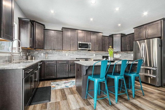 18734 Leonard Ct, New Buffalo, MI 49117 - kitchen featuring appliances with stainless steel finishes, a sink, dark brown cabinets, light wood-style floors, and a breakfast bar area