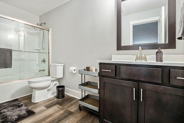 18734 Leonard Ct, New Buffalo, MI 49117 - bathroom featuring vanity, toilet, baseboards, enclosed tub / shower combo, and wood finished floors