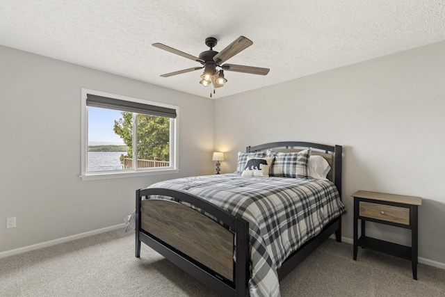 5384 Indian Trl, Frankfort, MI 49635 - carpeted bedroom with baseboards, a textured ceiling, ceiling fan, and a water view