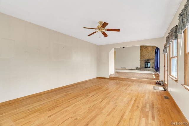 5562 Sheridan Line Rd, Croswell, MI 48422 - unfurnished living room featuring a large fireplace, light wood-style flooring, ceiling fan, and arched walkways