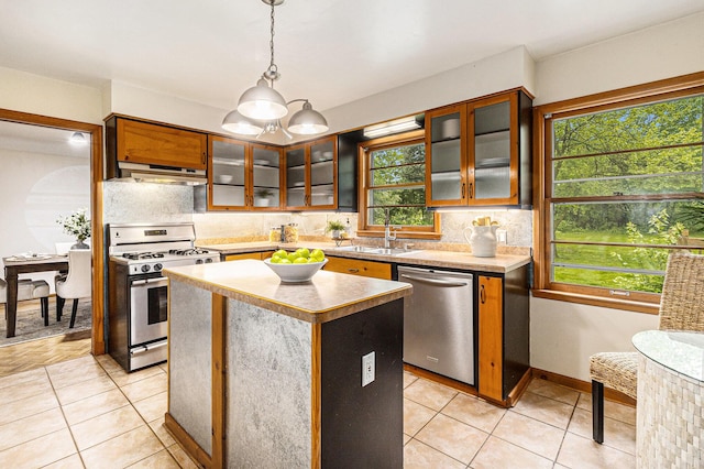 135 Barton Dr, Ann Arbor, MI 48105 - kitchen featuring appliances with stainless steel finishes, a sink, light tile patterned floors, tasteful backsplash, and a center island