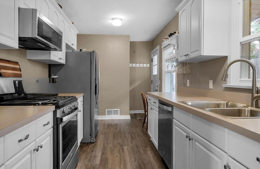 1155 Cadillac Dr SE, Grand Rapids, MI 49506 - kitchen with stainless steel appliances, a sink, light countertops, white cabinetry, and dark wood-style flooring